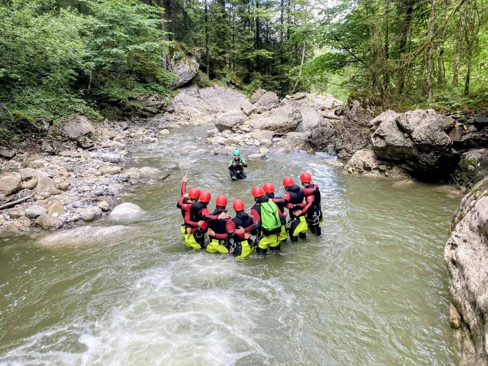 Canyoning-Gruppe zwischen Wasser und bewachsenen Felswänden